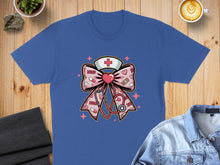Load image into Gallery viewer, Pink nurse bow with stethoscope and medical icons on a blue t-shirt.
