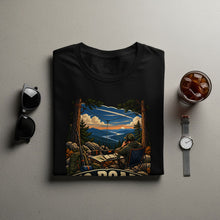 Load image into Gallery viewer, Black t-shirt with illustration of man operating radio outdoors overlooking a sunset river.
