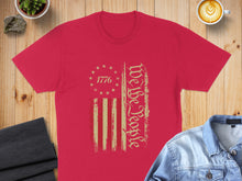Load image into Gallery viewer, Red t-shirt with distressed "We the People" text and American flag graphic.
