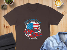Load image into Gallery viewer, Brown t-shirt with USA flag shield graphic and "Independence Day" text.
