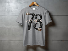 Load image into Gallery viewer, Grey t-shirt with "73" graphic made of a black cable and a waveform.
