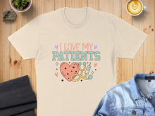 Load image into Gallery viewer, Cream t-shirt with "I LOVE MY PATIENTS" text and heart, stethoscope, and stars graphic.

