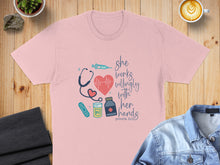 Load image into Gallery viewer, Light pink t-shirt with "she works willingly with her hands" and medical symbols.
