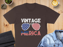 Load image into Gallery viewer, Brown t-shirt with "VINTAGE AMERICA" and sunglasses with American flag lenses.
