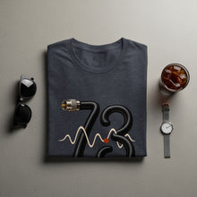 Load image into Gallery viewer, Dark grey t-shirt with black hose forming number 73 and beige waveform.
