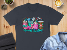 Load image into Gallery viewer, Medical Assistant graphic with coffee cups and medical icons on dark gray t-shirt.
