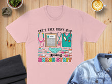 Load image into Gallery viewer, Pink t-shirt with "Can't Talk Right Now Doing Nurse Stuff" and medical icons.
