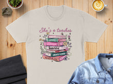 Load image into Gallery viewer, T-shirt with "She's a teacher" and stacked books with inspirational words.
