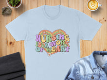 Load image into Gallery viewer, Light blue t-shirt with "Nursing is a work of heart" text in colorful retro font.
