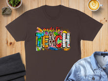 Load image into Gallery viewer, Brown t-shirt with "made to TEACH" graphic featuring colorful school supplies.
