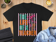 Load image into Gallery viewer, Black t-shirt with "The Life of a Teacher" text and a pink bow.
