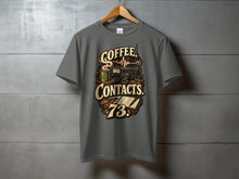 Load image into Gallery viewer, T-shirt graphic with "Coffee Contacts 73" text, coffee mug, radio, microphone, and notebook.
