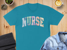 Load image into Gallery viewer, Teal t-shirt with "NURSE" text in colorful, patterned letters.
