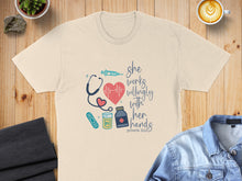 Load image into Gallery viewer, Cream t-shirt with "she works willingly with her hands" text and medical icons.
