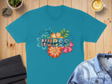 Load image into Gallery viewer, Turquoise t-shirt with floral "Nurse" graphic on a wooden surface.
