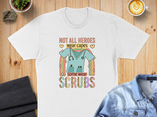 Load image into Gallery viewer, White t-shirt with graphic of scrubs, stethoscope, and rainbow with text "NOT ALL HEROES wear CAPES, some wear SCRUBS".
