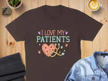 Load image into Gallery viewer, Brown t-shirt with "I Love My Patients" text and heart, stethoscope, and syringe graphic.
