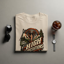 Load image into Gallery viewer, Cream t-shirt with "Low Power. High Expectations" graphic, surrounded by sunglasses and a drink.
