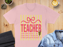 Load image into Gallery viewer, Pink t-shirt with "TEACHER" and text about rocking it.
