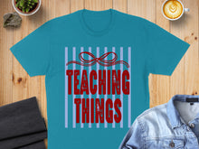 Load image into Gallery viewer, Teal t-shirt with red text "TEACHING THINGS" on blue stripes.
