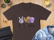 Load image into Gallery viewer, Brown t-shirt with "Peace Love Radiology" text and radiology-themed graphic.
