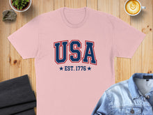 Load image into Gallery viewer, Pink t-shirt with "USA EST. 1776" in blue and red lettering.
