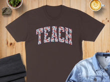 Load image into Gallery viewer, Brown t-shirt with "TEACH" printed in red, white, and blue floral pattern.
