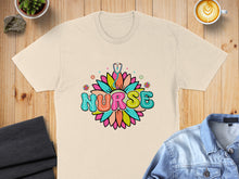 Load image into Gallery viewer, Cream t-shirt with "NURSE" text in colorful floral lettering and a stethoscope.
