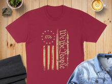 Load image into Gallery viewer, Burgundy t-shirt with distressed "We the People" text and American flag design.
