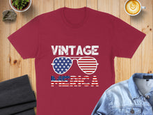 Load image into Gallery viewer, Maroon t-shirt with "VINTAGE AMERICA" text and patriotic sunglasses.
