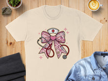 Load image into Gallery viewer, Light beige t-shirt featuring a pink nurse's hat and stethoscope with XOXO hearts.
