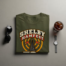 Load image into Gallery viewer, Olive green t-shirt with "Shelby Hamfest" text and broadcast tower graphic.
