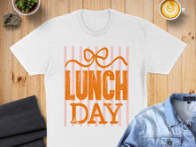 Load image into Gallery viewer, White t-shirt with orange "LUNCH DAY" text and bow graphic.
