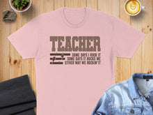 Load image into Gallery viewer, Pink t-shirt with "TEACHER SOME DAYS I ROCK IT SOME DAYS IT ROCKS ME EITHER WAY WE ROCKIN' IT" text.
