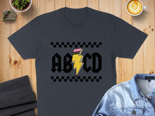 Load image into Gallery viewer, Dark gray t-shirt with AC/DC lightning bolt graphic on a wooden background.
