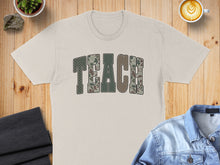 Load image into Gallery viewer, Cream t-shirt with "TEACH" in camouflage block letters.
