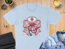 Load image into Gallery viewer, Light blue t-shirt with pink bow, stethoscope, and red cross graphic.
