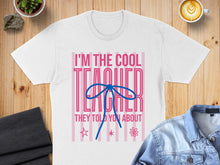 Load image into Gallery viewer, White t-shirt with "I'M THE COOL TEACHER THEY TOLD YOU ABOUT" text and pink stripes.
