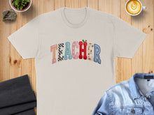 Load image into Gallery viewer, Cream t-shirt with "TEACHER" text in colorful, patterned letters.
