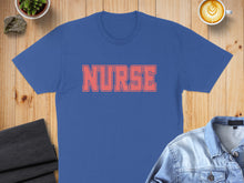 Load image into Gallery viewer, Blue t-shirt with "NURSE" in coral text, flat lay with coffee and denim jacket.
