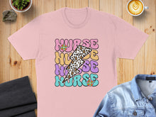 Load image into Gallery viewer, Pink t-shirt with "Nurse" text in colorful lightning bolts and floral patterns.
