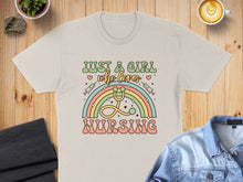 Load image into Gallery viewer, Cream t-shirt with "Just a girl who loves nursing" and rainbow stethoscope design.

