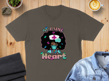 Load image into Gallery viewer, Brown t-shirt with graphic of a nurse with curly hair and butterflies, text reads "Nursing is a work of Heart".
