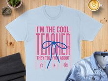 Load image into Gallery viewer, Light blue t-shirt with "I'm The Cool Teacher" and a blue ribbon graphic.

