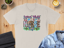 Load image into Gallery viewer, "Luvin' That Nurse Life" text with stethoscope, heart, and syringe graphic on beige t-shirt.
