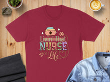 Load image into Gallery viewer, Burgundy t-shirt with colorful "Livin' That Nurse Life" text and stethoscope graphic.
