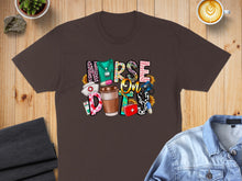Load image into Gallery viewer, Nurse life design with coffee cup, stethoscope, and medical icons on brown t-shirt.
