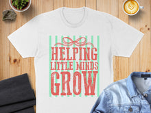 Load image into Gallery viewer, White t-shirt with "HELPING LITTLE MINDS GROW" in distressed red and green lettering.
