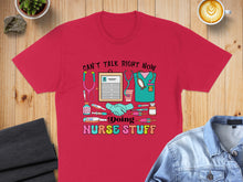 Load image into Gallery viewer, Red t-shirt with colorful nurse-themed graphics and text.
