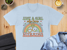 Load image into Gallery viewer, Light blue t-shirt with "Just a girl who loves nursing" text and rainbow stethoscope.

